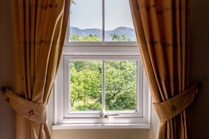 Ein Fenster mit Blick auf eine grüne Landschaft und Berge.