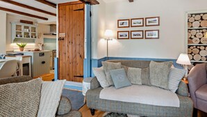 A cozy living room with a sofa, armchairs, a coffee table, a dining table, and a kitchen in the background. - 3 Bed in Ulverston (oc-sz445) (Satterthwaite)