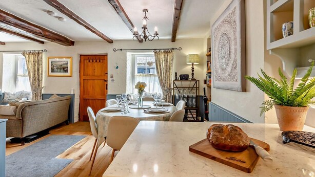 A cozy kitchen with a marble countertop, wooden beams, a chandelier, and a dining area with a table set for four. - 3 Bed in Ulverston (oc-sz445) (Satterthwaite)