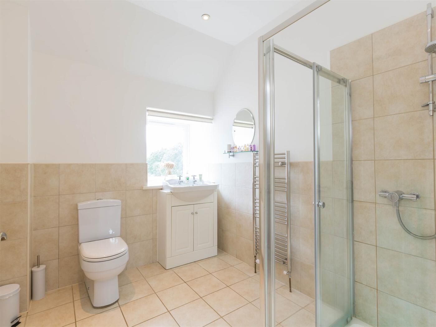 Un bagno con il water, lavandino, specchio e zona doccia.