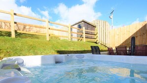 Een hottub met een houten omheining en een gebouwtje op de achtergrond.