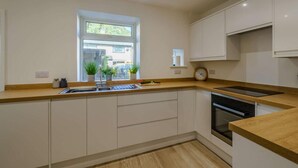 Una cocina moderna con ventana, armarios empotrados, un fregadero y un horno.