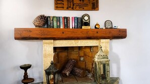 Ein Kamin mit hölzernem Sims, der Bücher und eine Uhr trägt.