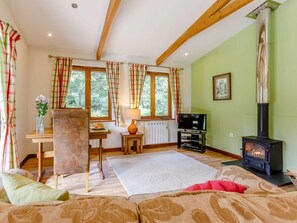 A cozy living room with a fireplace, wooden beams, a TV, and a dining area. - 1 Bed in Holsworthy (oc-85561) (Bradworthy)