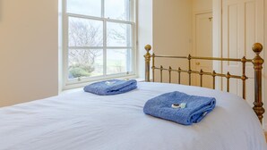 Ein Schlafzimmer mit großem Fenster, einem Bett mit Metallkopfteil und einer Tür.