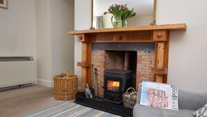 A cozy living room with a fireplace, a sofa, a striped rug, and a magazine on the armrest. - 2 Bed in Applecross (oc-ca422) (Applecross)