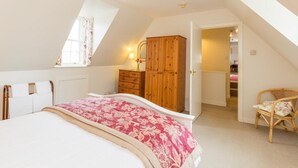 A bedroom with a bed, a wooden wardrobe, a chair, and a window with curtains. - 2 Bed in Applecross (oc-ca422) (Applecross)