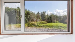 Ein Fenster mit Blick auf eine Wiese und Bäume.