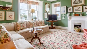 Un salon comprenant un canapé, un téléviseur, une cheminée et des œuvres d’art encadrées accrochées aux murs.