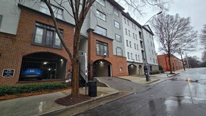 Un edificio de varios pisos con fachada de ladrillo, entrada para visitantes y zona de estacionamiento.
