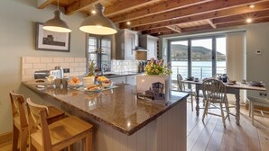 A kitchen with wooden beams, a large island with seating, and a view of a body of water. - 2 Bed in Inverness (oc-ca324) (Inverness)