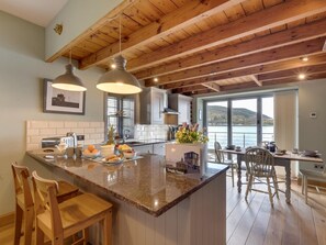 A kitchen with wooden beams, a large island with seating, and a view of a body of water. - 2 Bed in Inverness (oc-ca324) (Inverness)