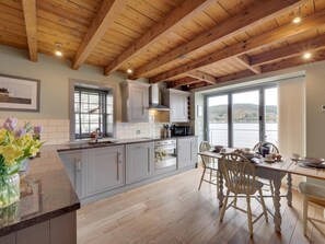 A kitchen with wooden beams, a dining area with a table and chairs, and a view of a lake. - 2 Bed in Inverness (oc-ca324) (Inverness)