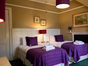 A hotel room with two beds, a fireplace, and a painting on the wall.