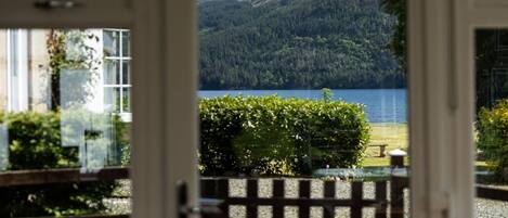 A view through a door of a mountainous landscape with a lake.