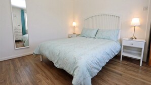 A bedroom with a bed, two bedside tables with lamps, a mirror, and a wardrobe. - 3 Bed in Isle Of Skye (oc-ca298) (Uig)