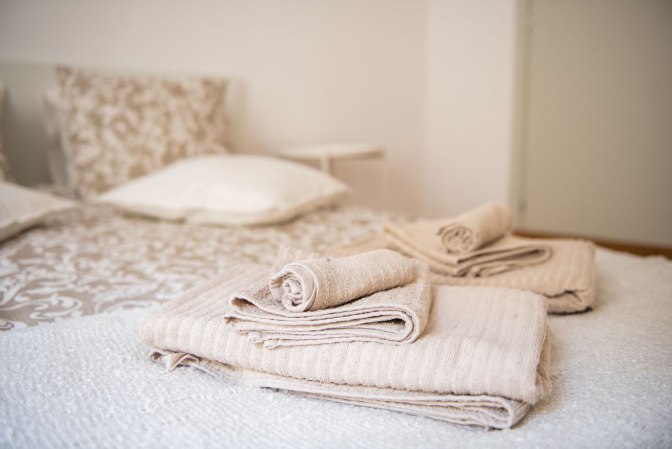 Una cama bien hecha con toallas dobladas, un edredón estampado y una almohada.