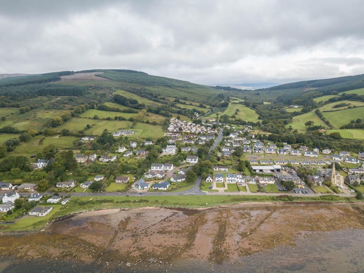 A coastal village with houses, a church, and a road leading into the village.