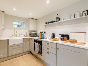 A modern kitchen with white cabinets, a built-in oven, a coffee maker, and a bread box on the countertop. - 2 Bed in Ilfracombe (oc-76407) (Ilfracombe)