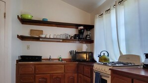 Una cocina con armarios de madera, estufa, microondas y hervidor.