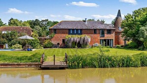 A brick house with a pond, a wooden dock, and a grassy lawn. - 5 Bed in Ashford (oc-76428) (Smarden)