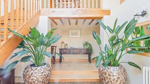 A staircase with wooden railings, a wooden bench, and two large potted plants with geometric-patterned pots. - 5 Bed in Ashford (oc-76428) (Smarden)
