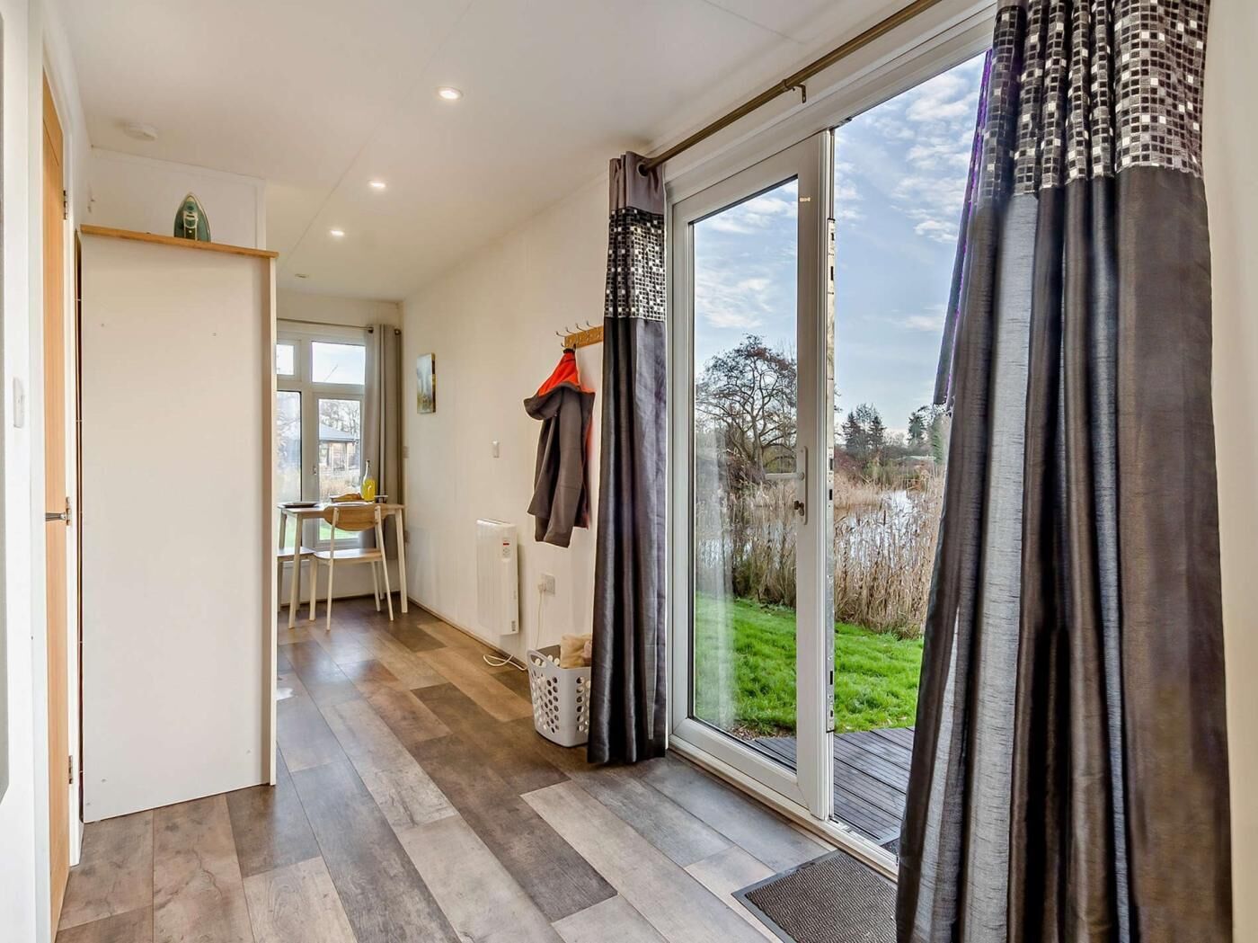 Une pièce dotée d’une grande porte-fenêtre coulissante donnant sur un jardin, d’une chaise, d’une table et d’un radiateur.
