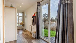 A room with a large sliding glass door to a garden, a chair, a table, and a radiator. - 1 Bed in Norwich (oc-76493) (East Harling)