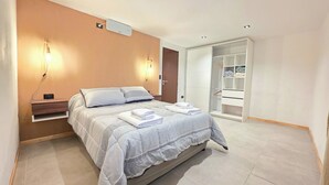 A modern bedroom with a bed, bedside tables, a wardrobe, and a walk-in closet.