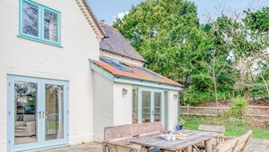 Ein Haus mit einer Terrasse, einem Holztisch und einem Stuhl.