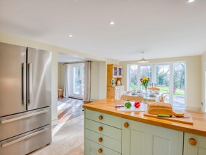 A modern kitchen with a stainless steel refrigerator, a wooden countertop, and a view of the garden through large windows. - 3 Bed in Wareham (oc-76648) (South Trigon)
