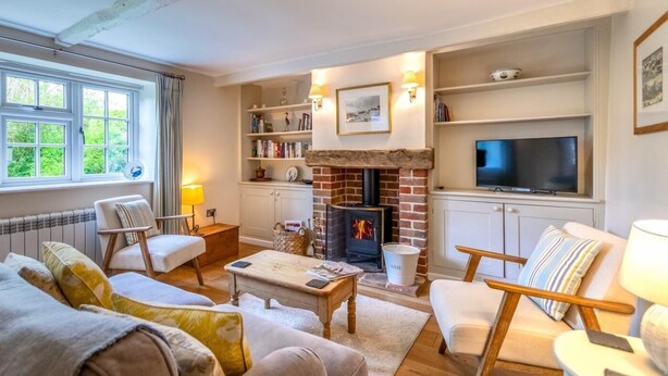 Una sala acogedora con chimenea, asientos cómodos, un televisor y una estantería.