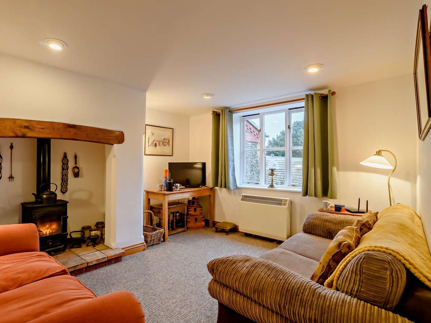 A cozy living room with a fireplace, a television, and a window with curtains.