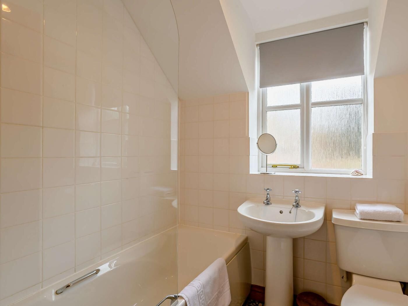 Et badeværelse med badekar, vask, toilet og et vindue med udsigt.