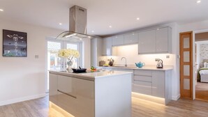 Une cuisine moderne dotée d’un îlot central, de meubles blancs et d’une hotte de cuisinière visible.
