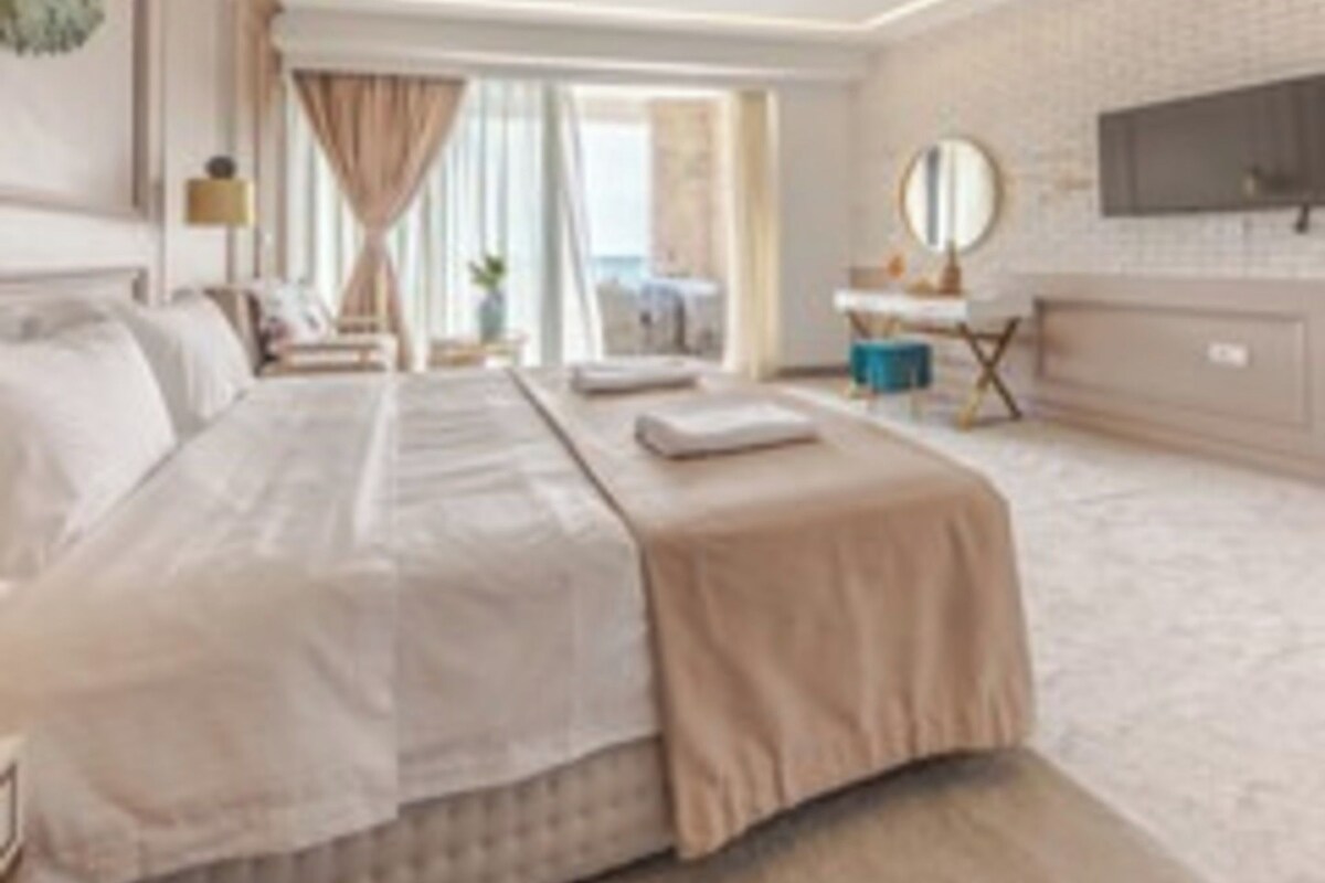 A hotel room with a large bed, a desk, a television, and a window.