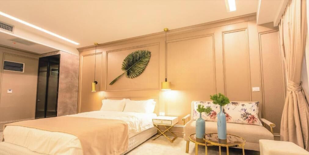 Ein Hotelzimmer mit Bett, Nachttisch, Stuhl und einem dekorativen Blatt an der Wand.