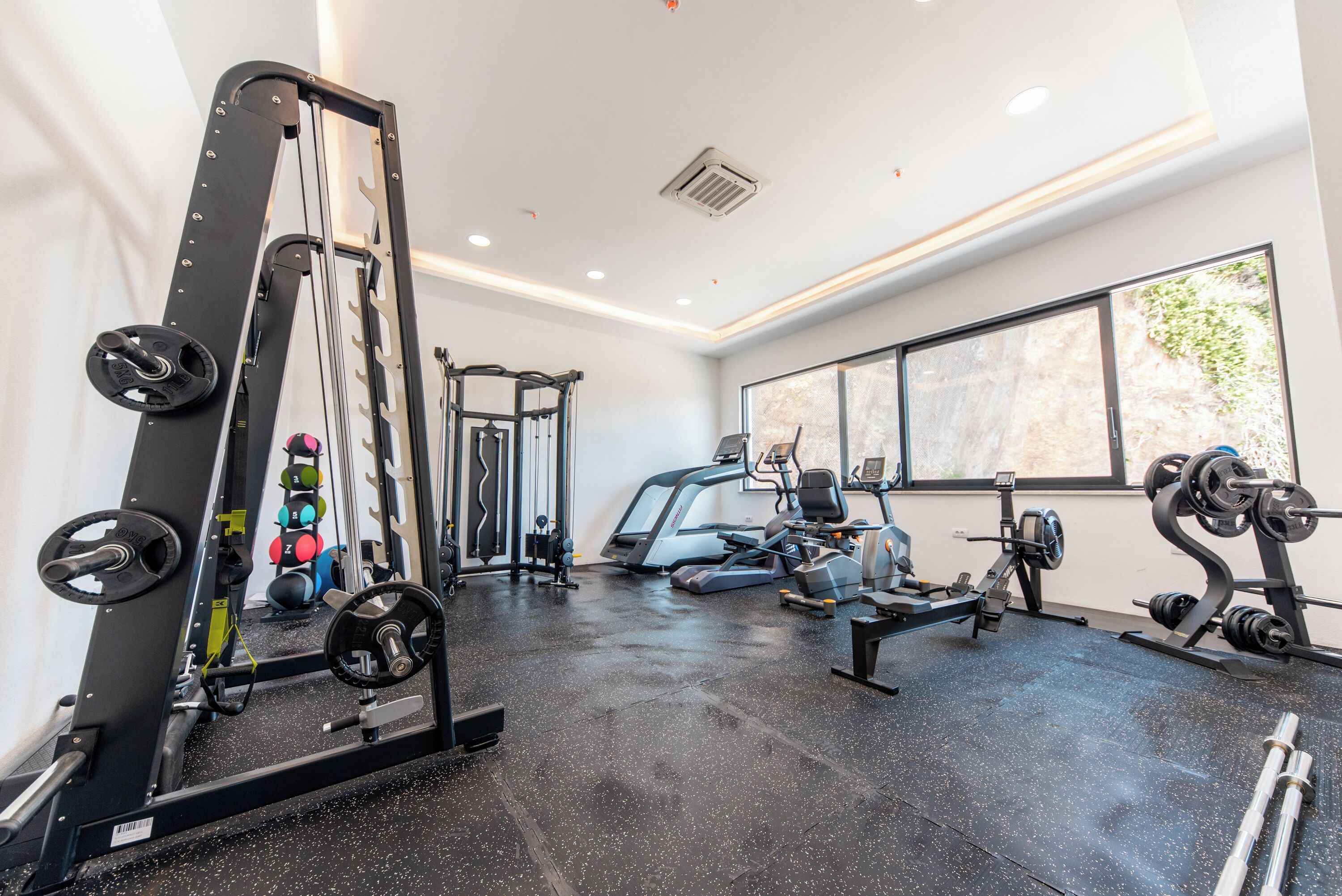 A gym with exercise equipment, a treadmill, and a large window.