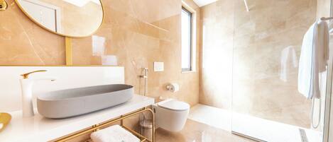 A modern bathroom with a large mirror, a vessel sink, a toilet, and a glass-enclosed shower.