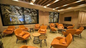 Un área de descanso moderna con sillones de cuero, un sofá y un ventanal con una pintura rupestre.
