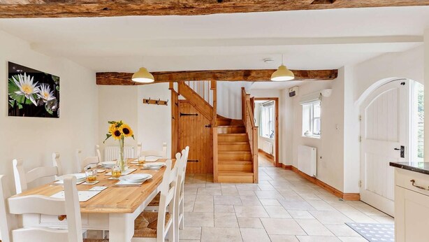 A dining area with a wooden table and chairs, a staircase, and a view of the outside. - 3 Bed in Church Stretton (oc-76621) (Rushbury)