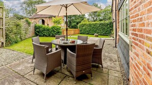 A patio with wicker furniture, a table, and a large umbrella. - 3 Bed in Church Stretton (oc-76621) (Rushbury)