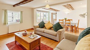 A cozy living room with a sofa, coffee table, and dining area with chairs and a table. - 3 Bed in Church Stretton (oc-76621) (Rushbury)