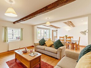 A cozy living room with a sofa, coffee table, and dining area with chairs and a table. - 3 Bed in Church Stretton (oc-76621) (Rushbury)