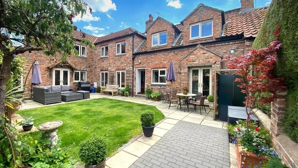 A brick house with a patio, outdoor seating, and a well-maintained lawn. - 5 Bed in York (oc-77267) (Green Hammerton)