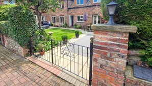 A brick house with a paved driveway, a lawn, and a gate. - 5 Bed in York (oc-77267) (Green Hammerton)