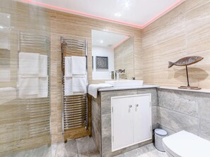Een moderne badkamer met een glazen douchecabine, een wit wastafelmeubel, een kast en een lamp in de vorm van een vis.