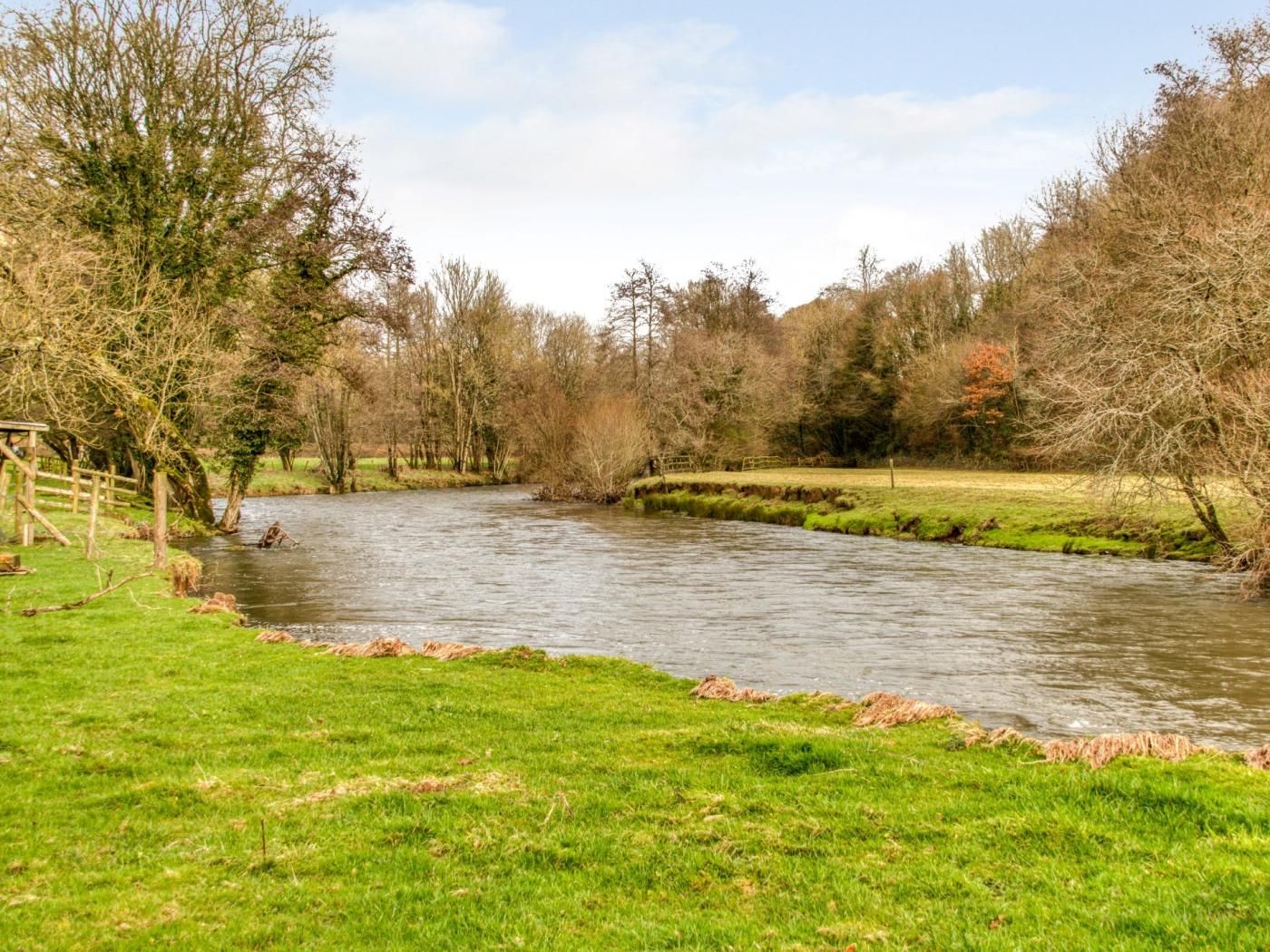 A river flowing through a park with grassy banks and trees.
