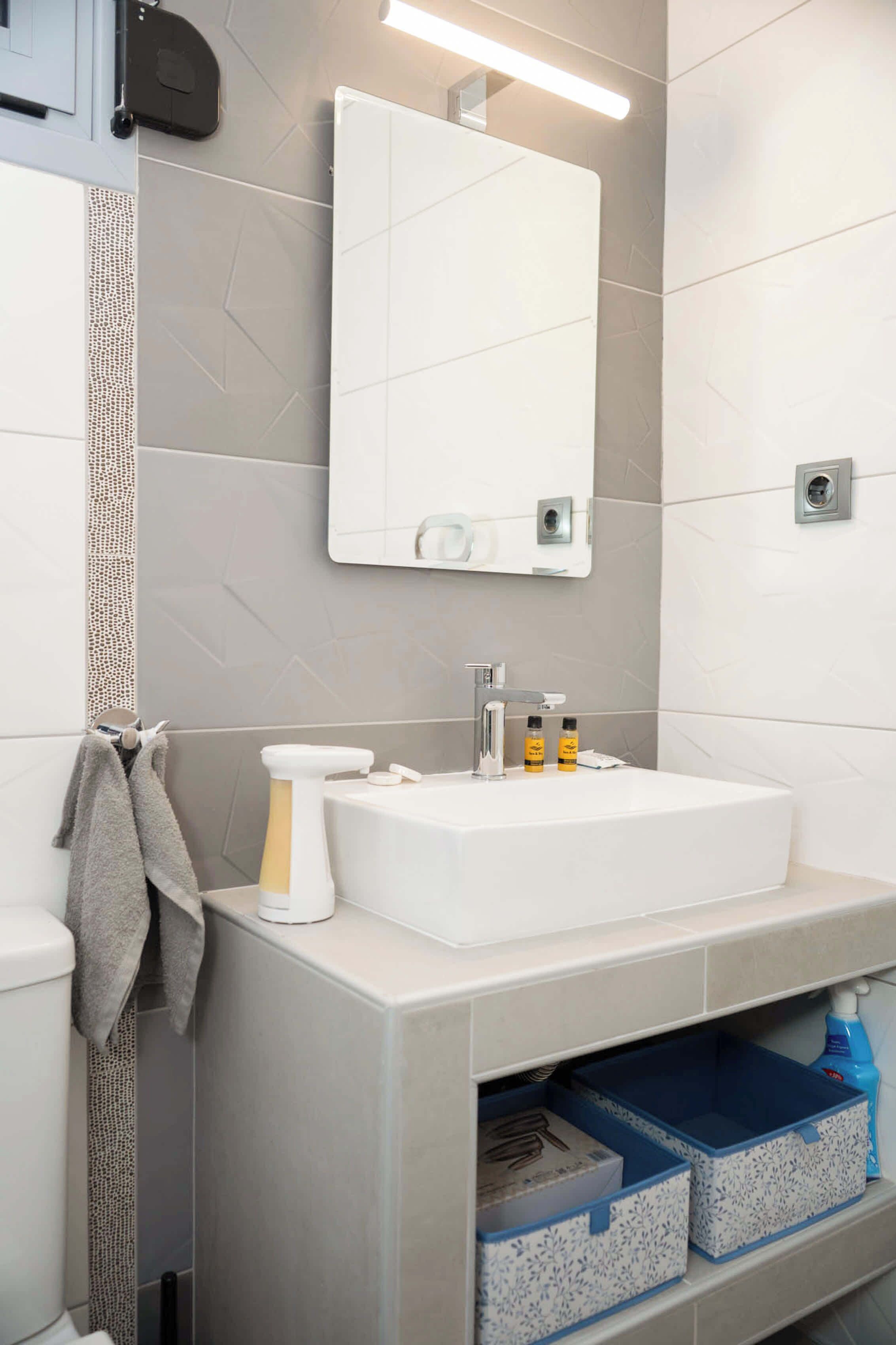 A bathroom with a white sink, mirror, and storage boxes.