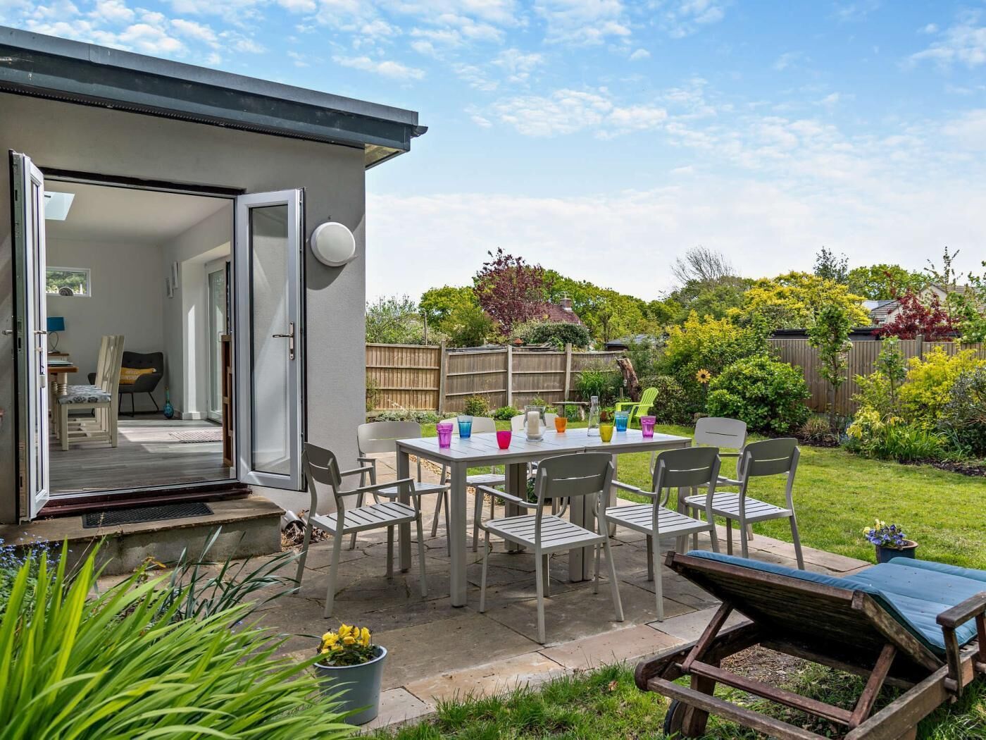 A patio area with a table and chairs, a covered seating area, and a view of a garden.